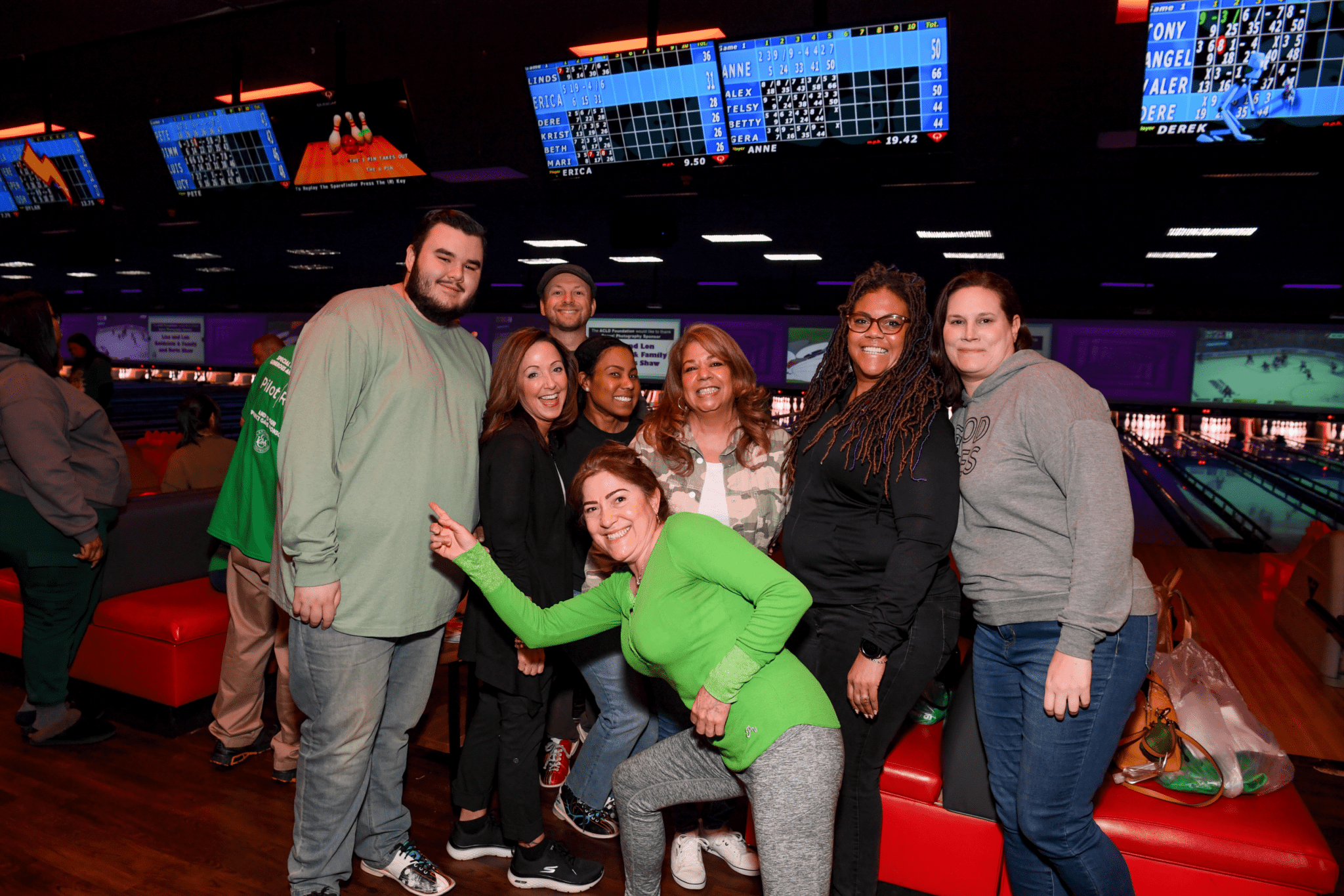 A group of individuals posing and smiling at a bowling alley